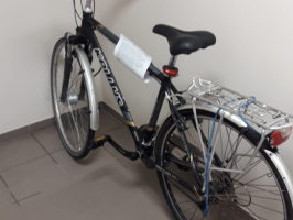 melns velosipēds atstutēts pret pelēku sienu