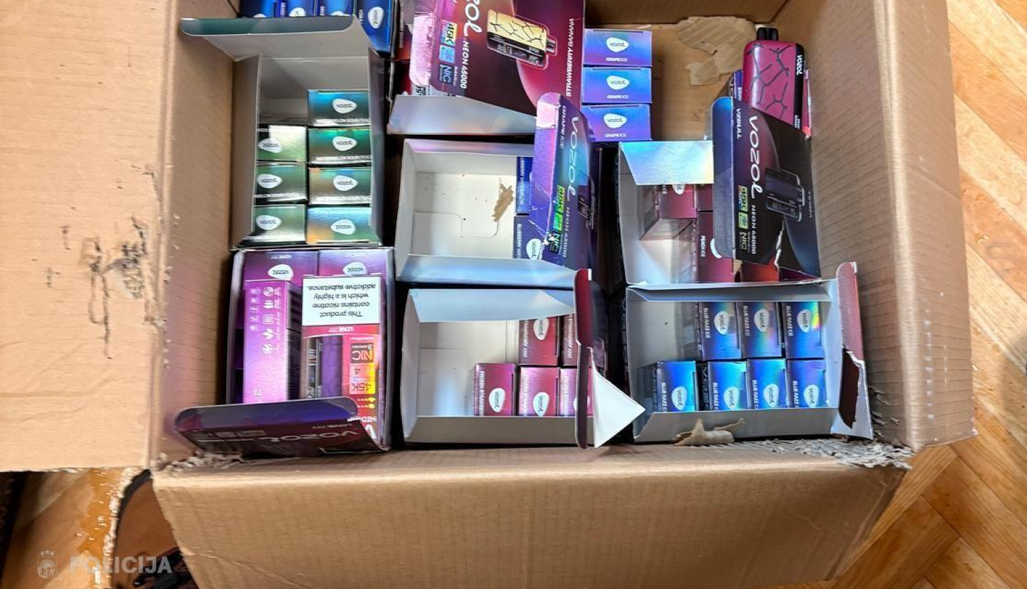 Kartona kaste ar elektroniskajām cigaretēm, kas novietota uz grīdas