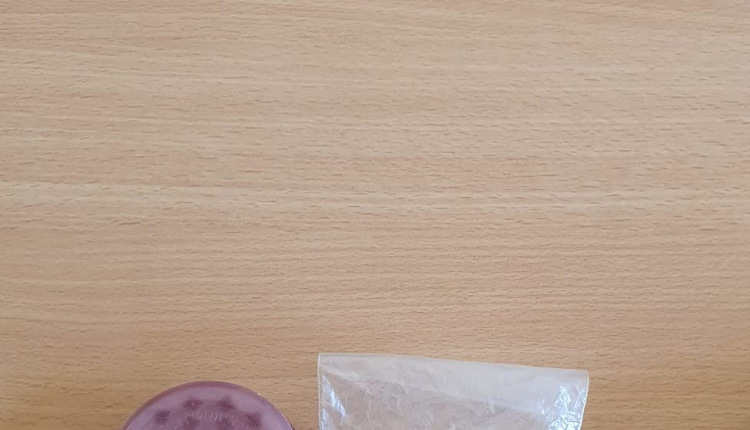 Caurspīdīgs maisiņš, kurā redzamas četras savirpinātas folija bumbiņas un rozā apaļš trauciņš blakus