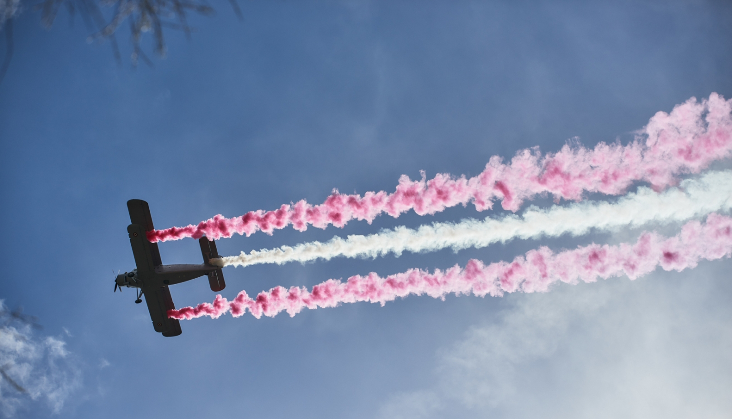 Lidmašīna debesīs veido krāsainu sarkanbaltsarkanu dūmu līnijas debesīs