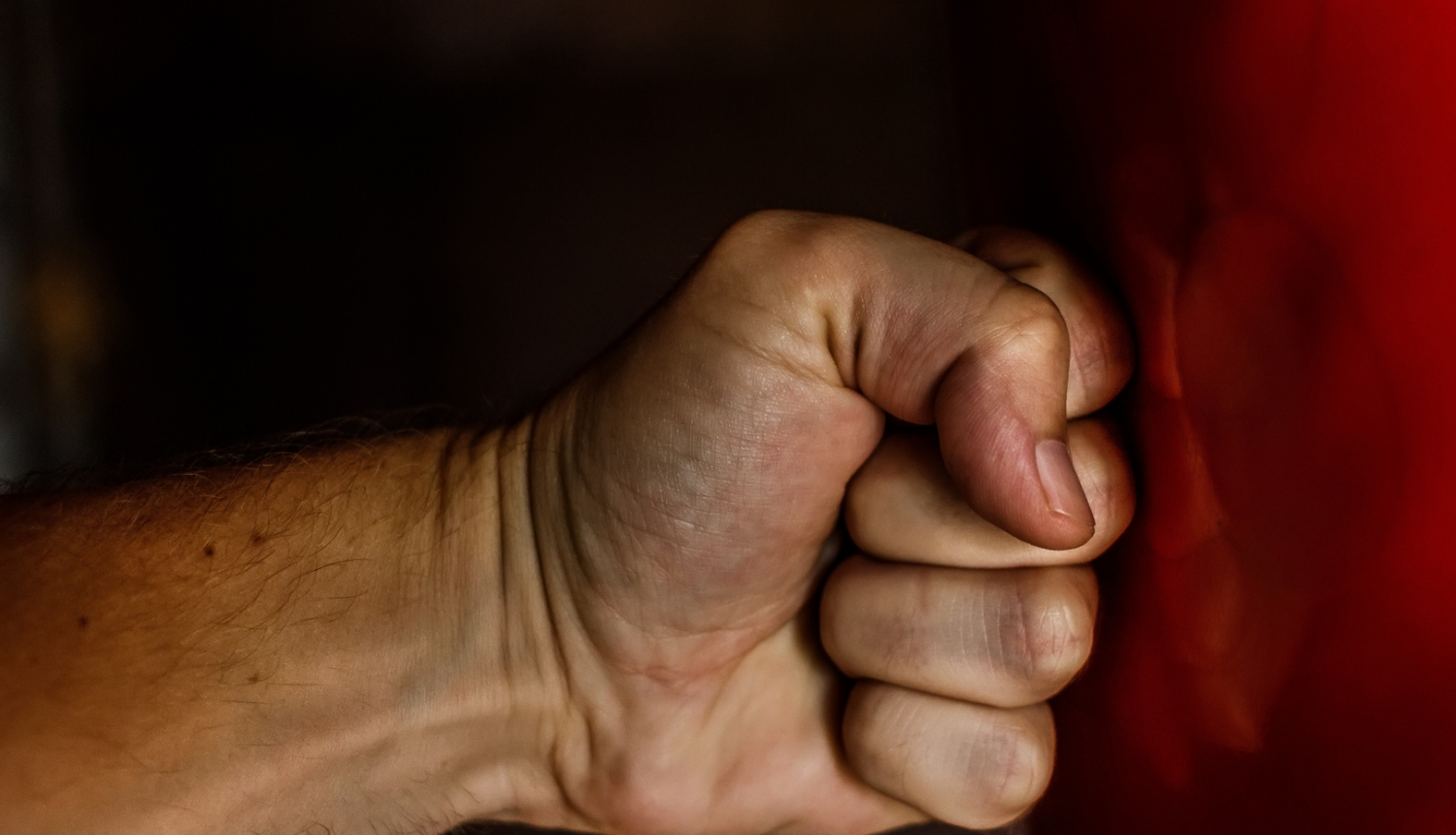 Cilvēka dūre sit pa sarkanu boksa maisu