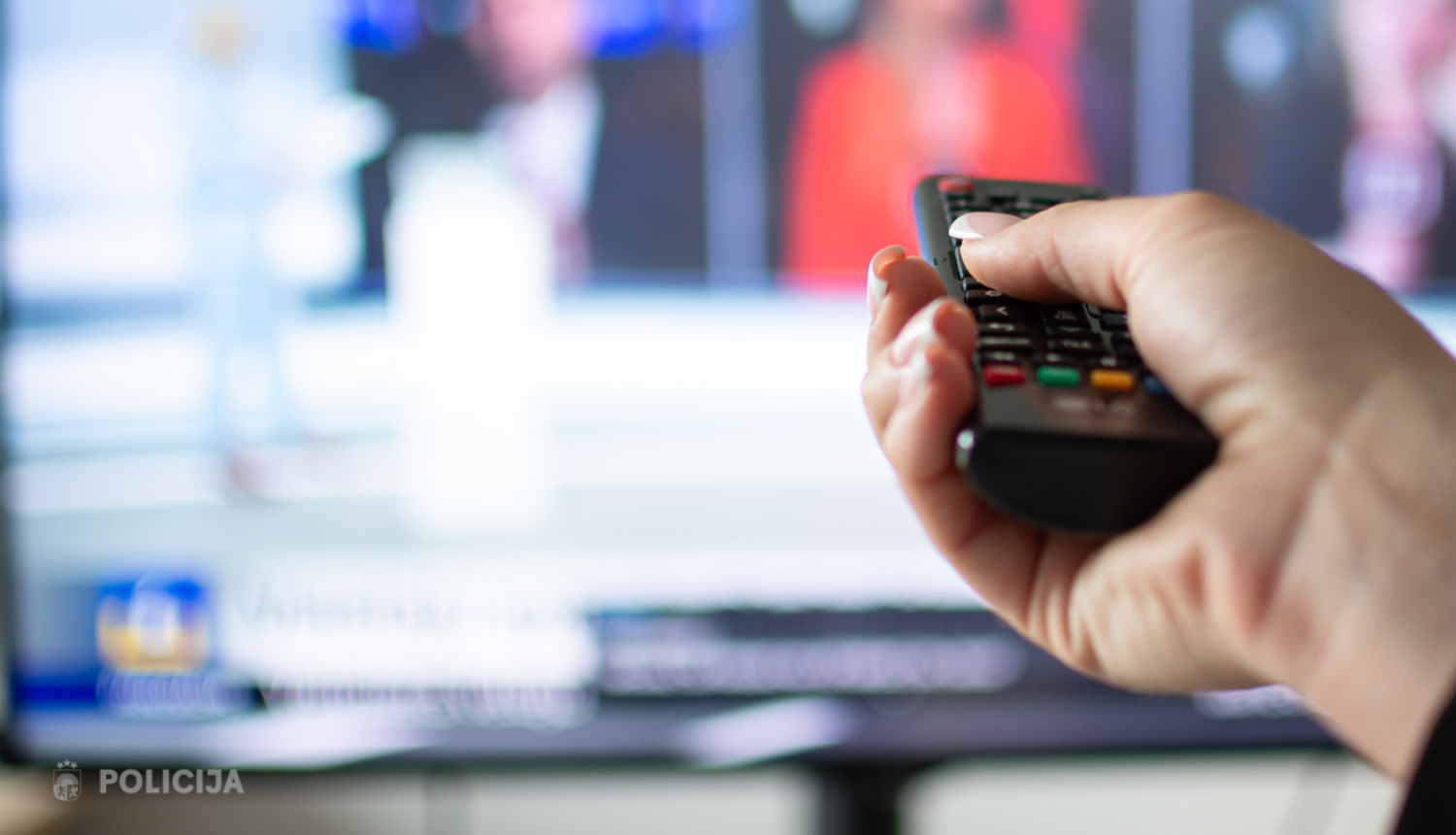 cilvēks tur rokās pulti pret televizoru