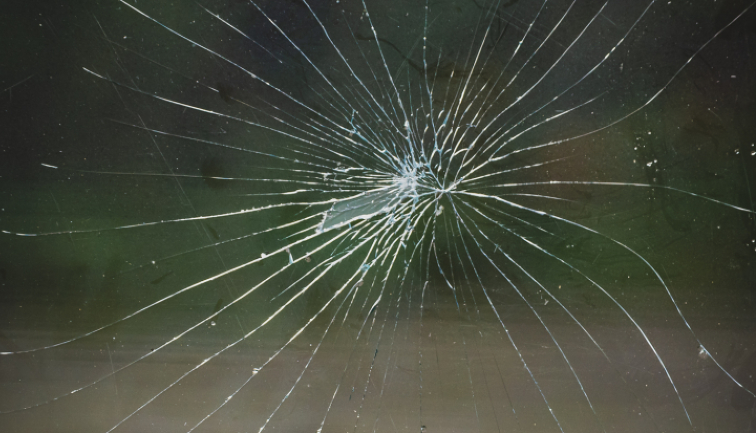 tuvplāns ar stipri saplaisājušu stiklu pēc trieciena, plaisas radiāli izplešas no viena centrālā trieciena punkta