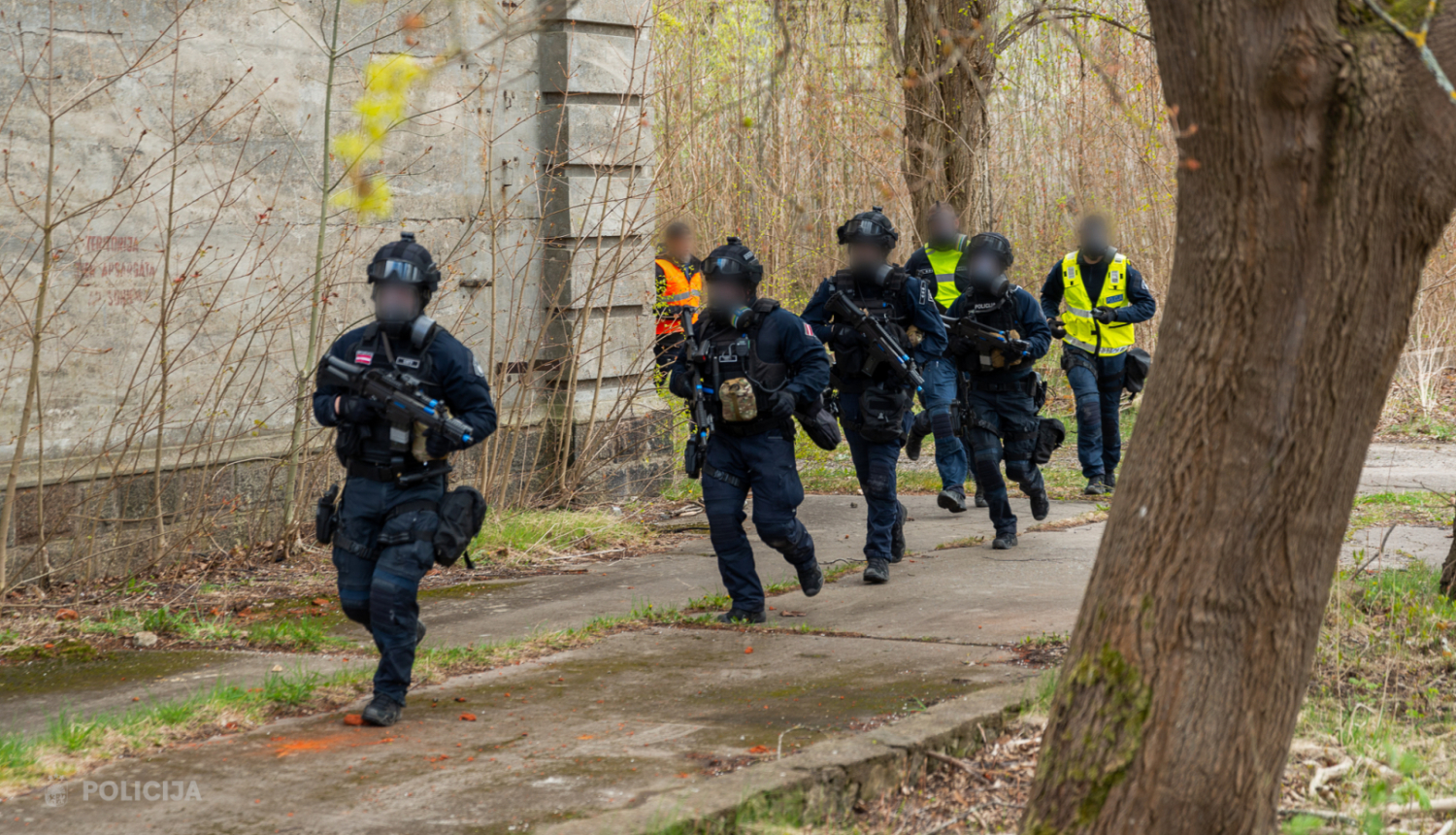 policistis ekipējumā skiren gar ēku