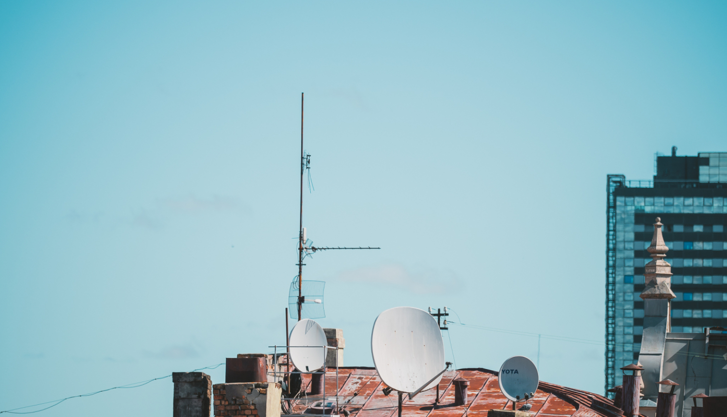 Ēkas jumts ar antenām un satelīta šķīvjiem pilsētvidē