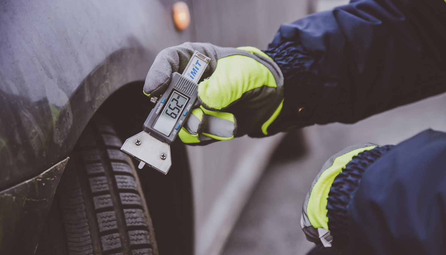 Automašīnas riepa, kurai ar mērierīci tiek mērīts protektoru dziļums