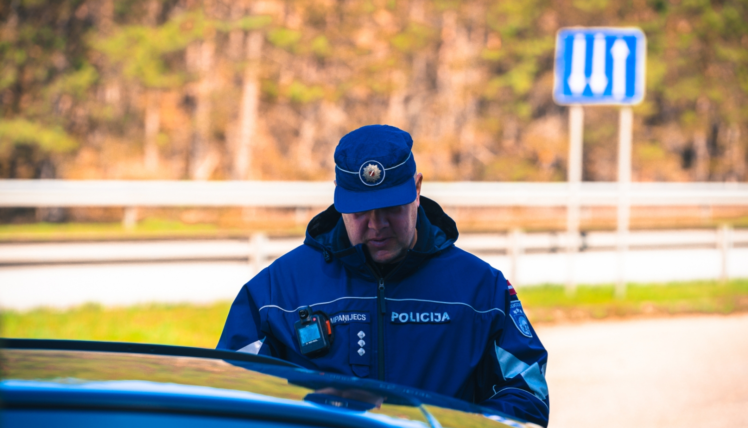 Valsts policijas darbinieks pie automašīnas