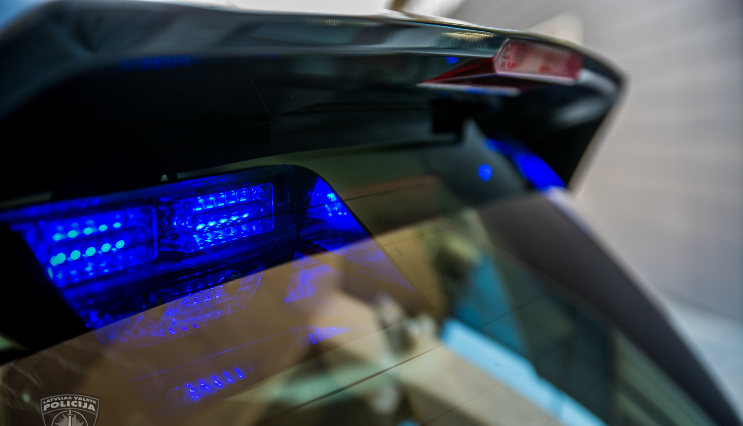 No ārpuses tuvplānā nofotografēta policijas automašīna, lai redzamas zilās gaismas