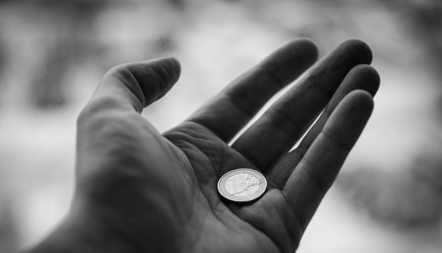 Melnbalts attēls, kurā redzams viens eiro atvērtā plaukstā