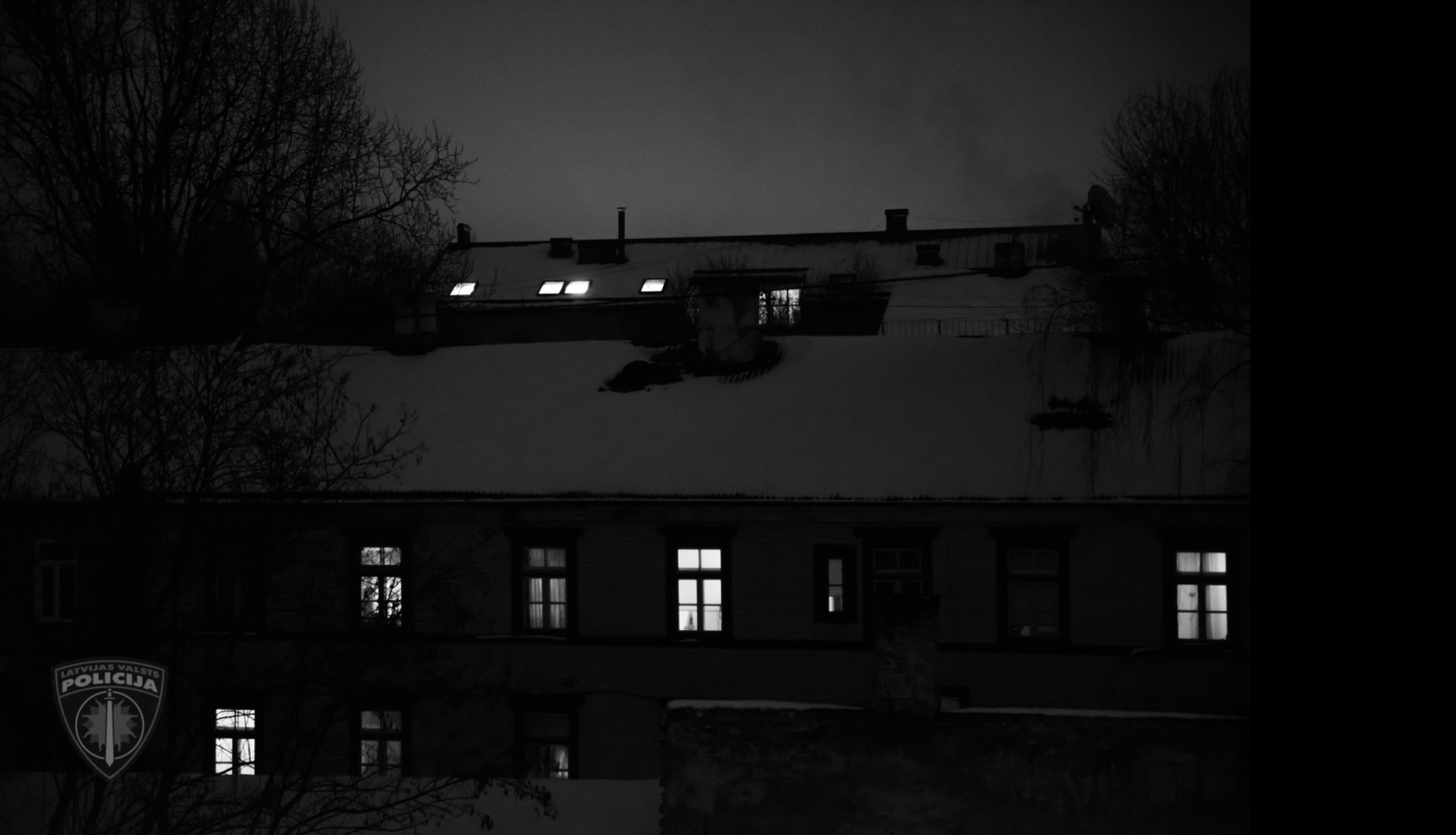 Nakts. Māja, kur daži logi gaiši, bet daži - tumši. 