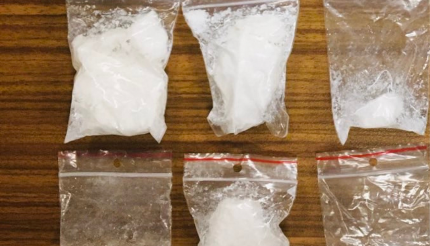 Seši caurspīdīgas plastmasas maisiņi, kuros ir baltas krāsas pulverveida viela un vienā vairākas baltas krāsas tabletes