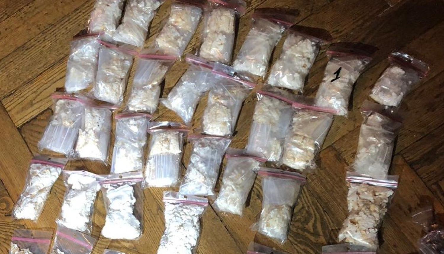 Uz grīdas vairāki caurspīdīga polietilēna maisiņi, kuros atrodas narkotiskās vielas