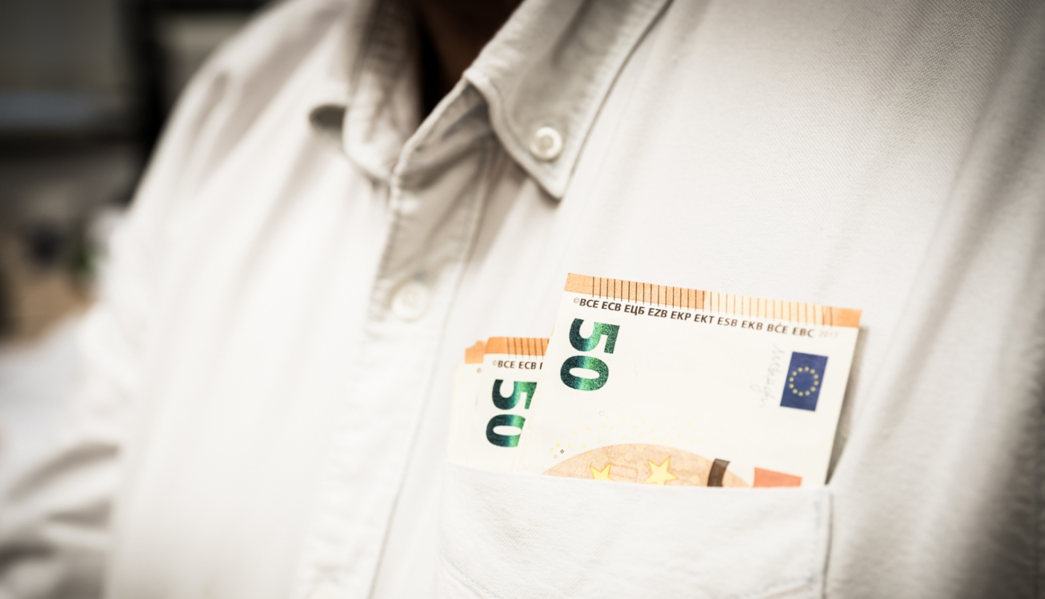 Banknotes ieliktas balta krekla kabatā