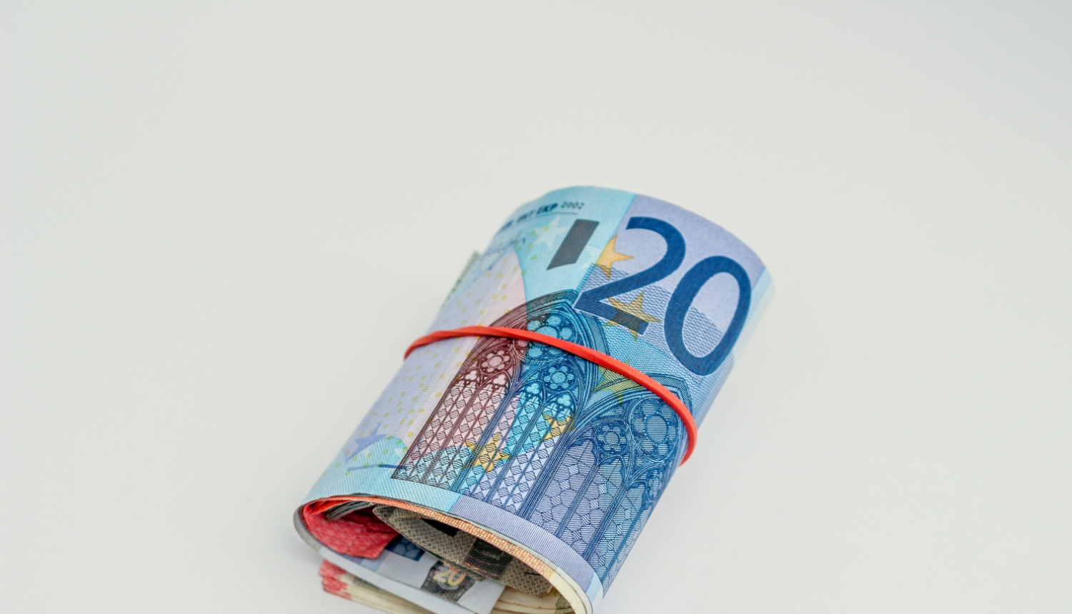 20 eiro banknote sarullēta kopā ar citu nominālu banknotēm un aplikta apkārt sarkana gumija