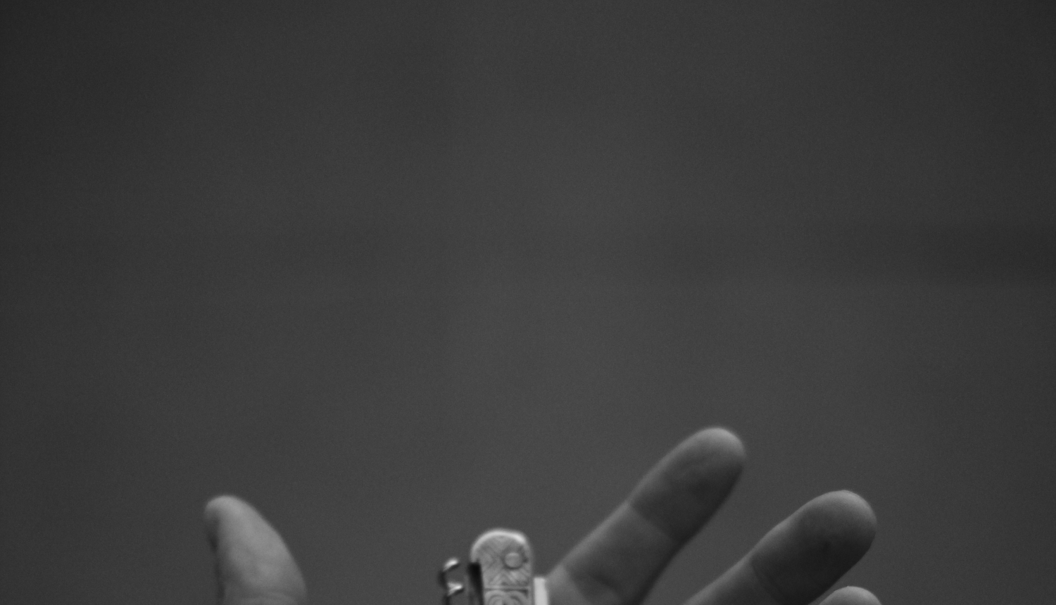 Cilvēka plaukstā ievietots saliekamais nazis. Plauksta atvērta, pavērsta uz augšu. Melnbaltā bilde.