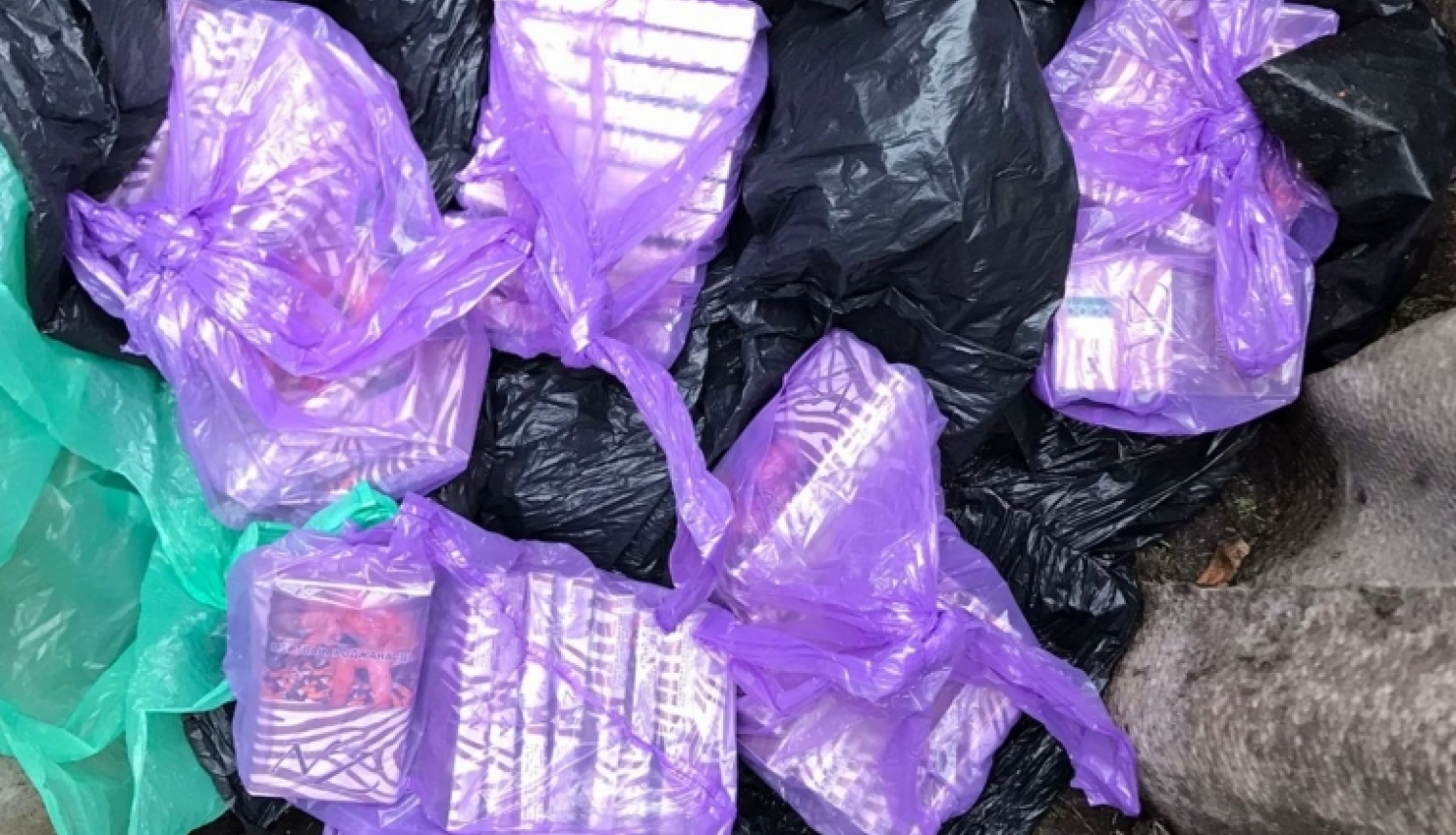uz zemes redzami lillā plastmasas maisos iepakoti nelegālo cigarešu bloki