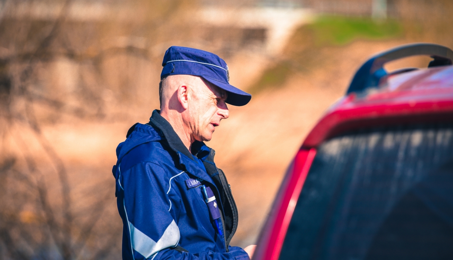 Valsts policijas darbinieks pie automašīnas