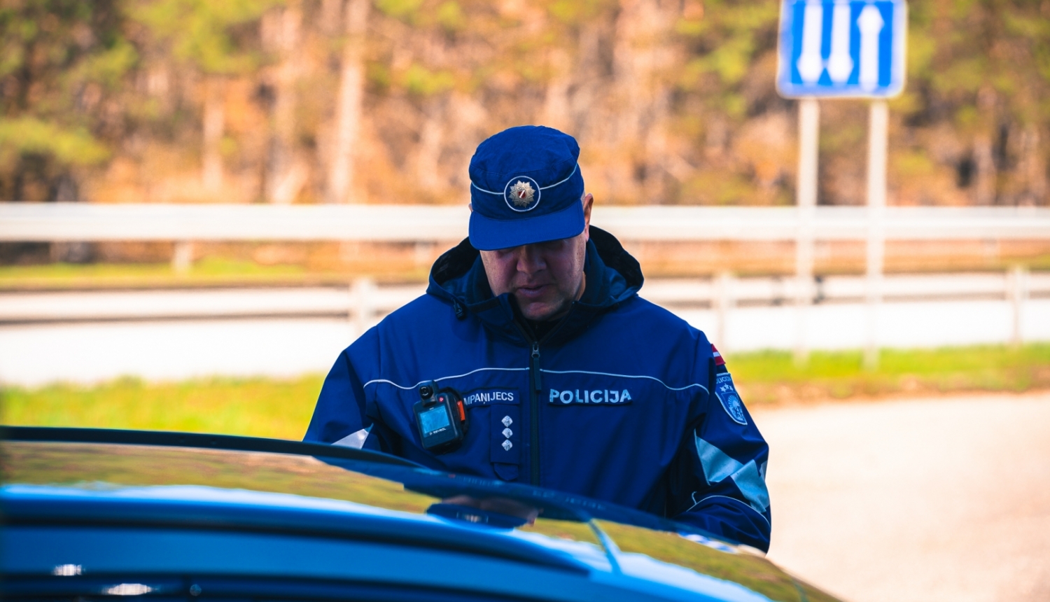 Valsts policijas darbinieks pie automašīnas