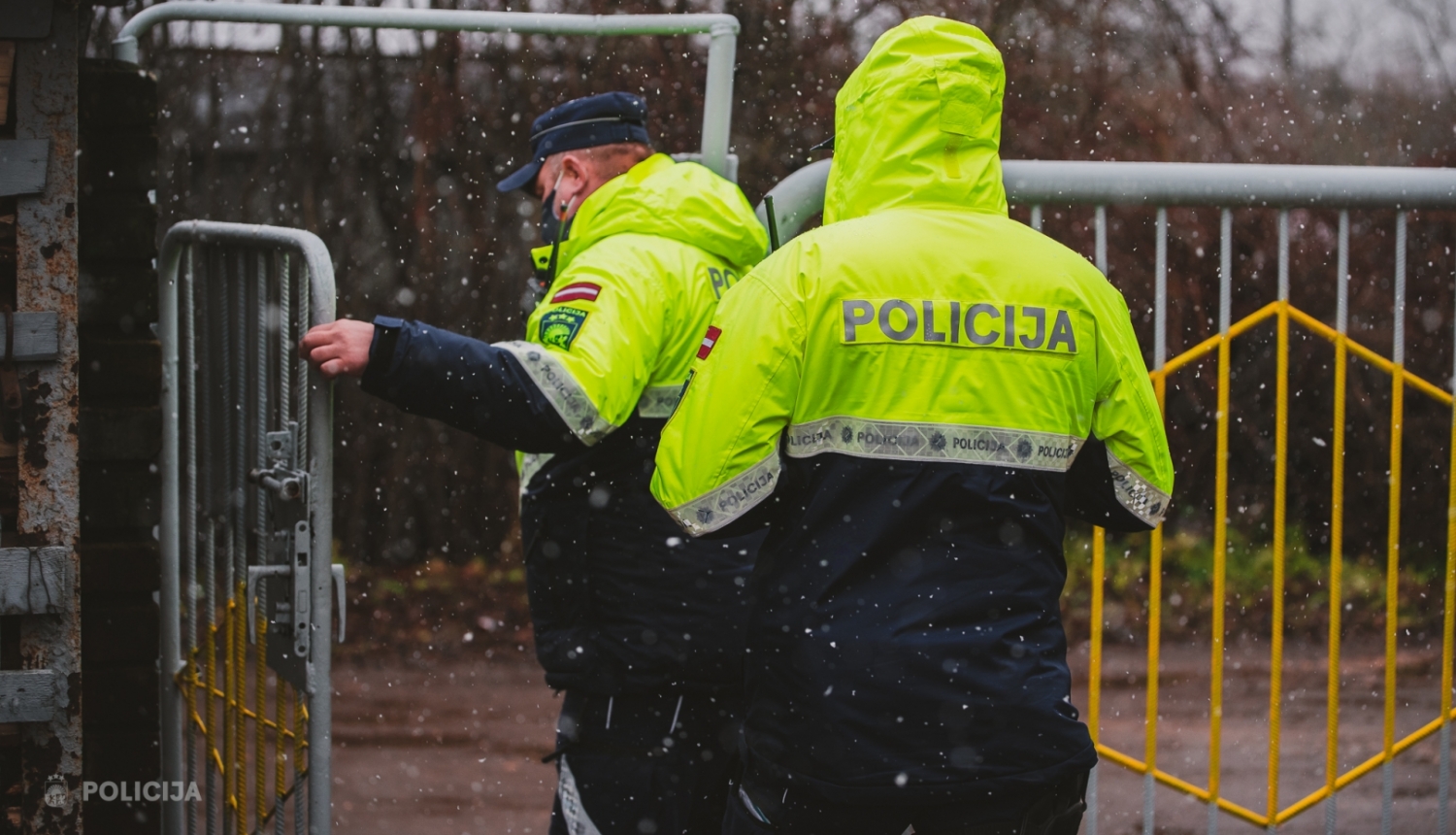 Policisti iet iekšā pagalmā pa atvērtiem vārtiem