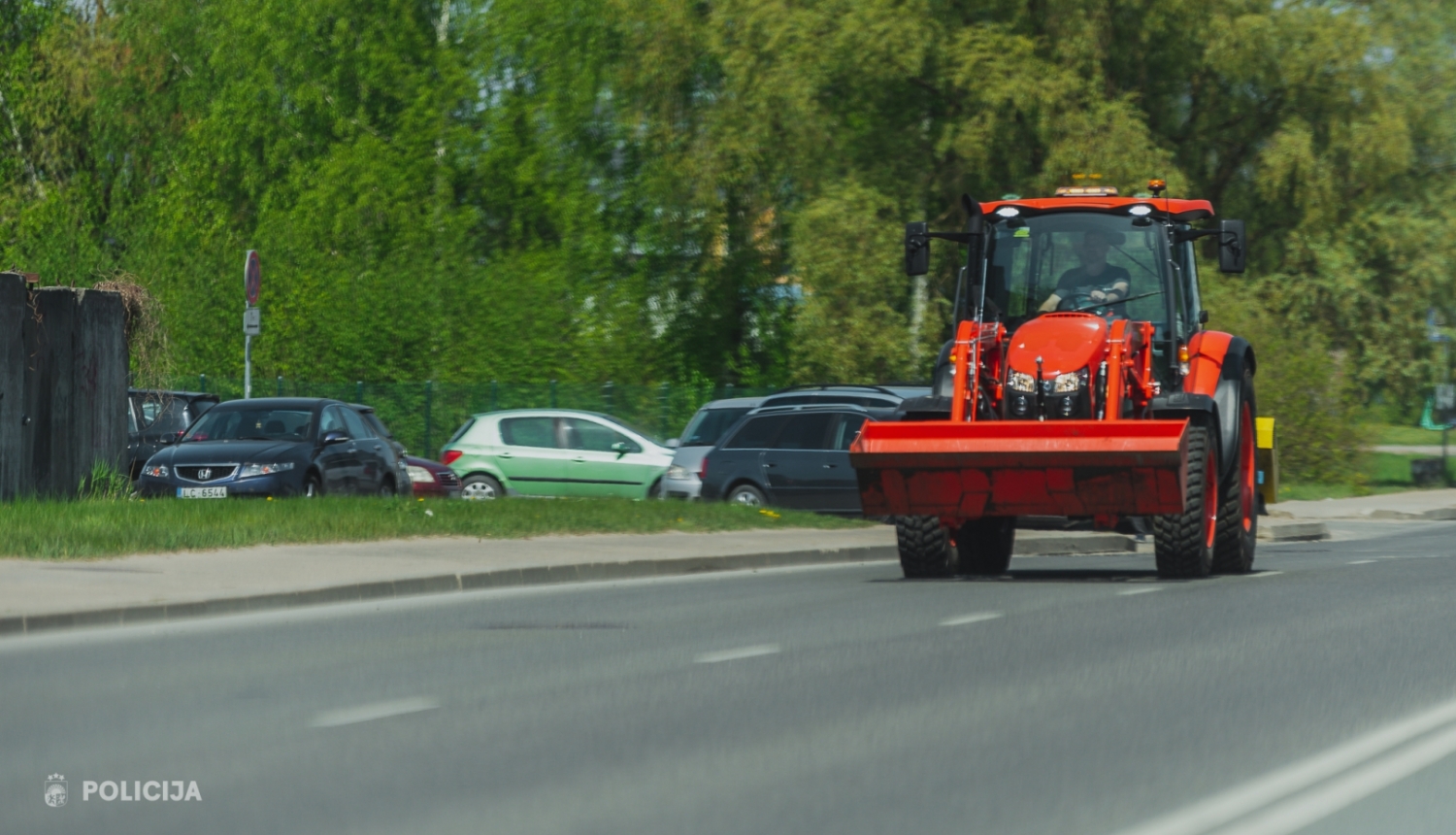 Sarkans traktors pārvietojas pa ielu