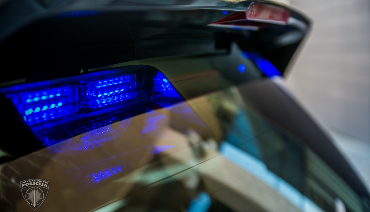 No ārpuses tuvplānā nofotografēta policijas automašīna, lai redzamas zilās gaismas