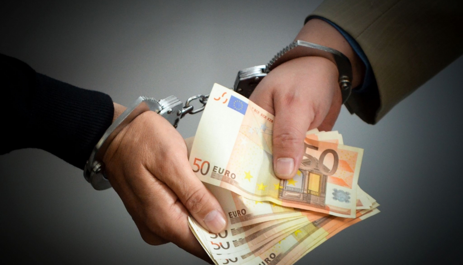 Ar rokudzelžiem sasaistītas divas rokas, kas tur daudz 50 eiro banknotes